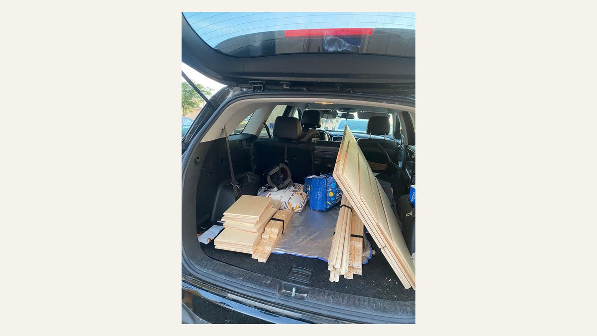 Real wooden flat-pack retail display components in a car, shown without cropping in compact horizontal format