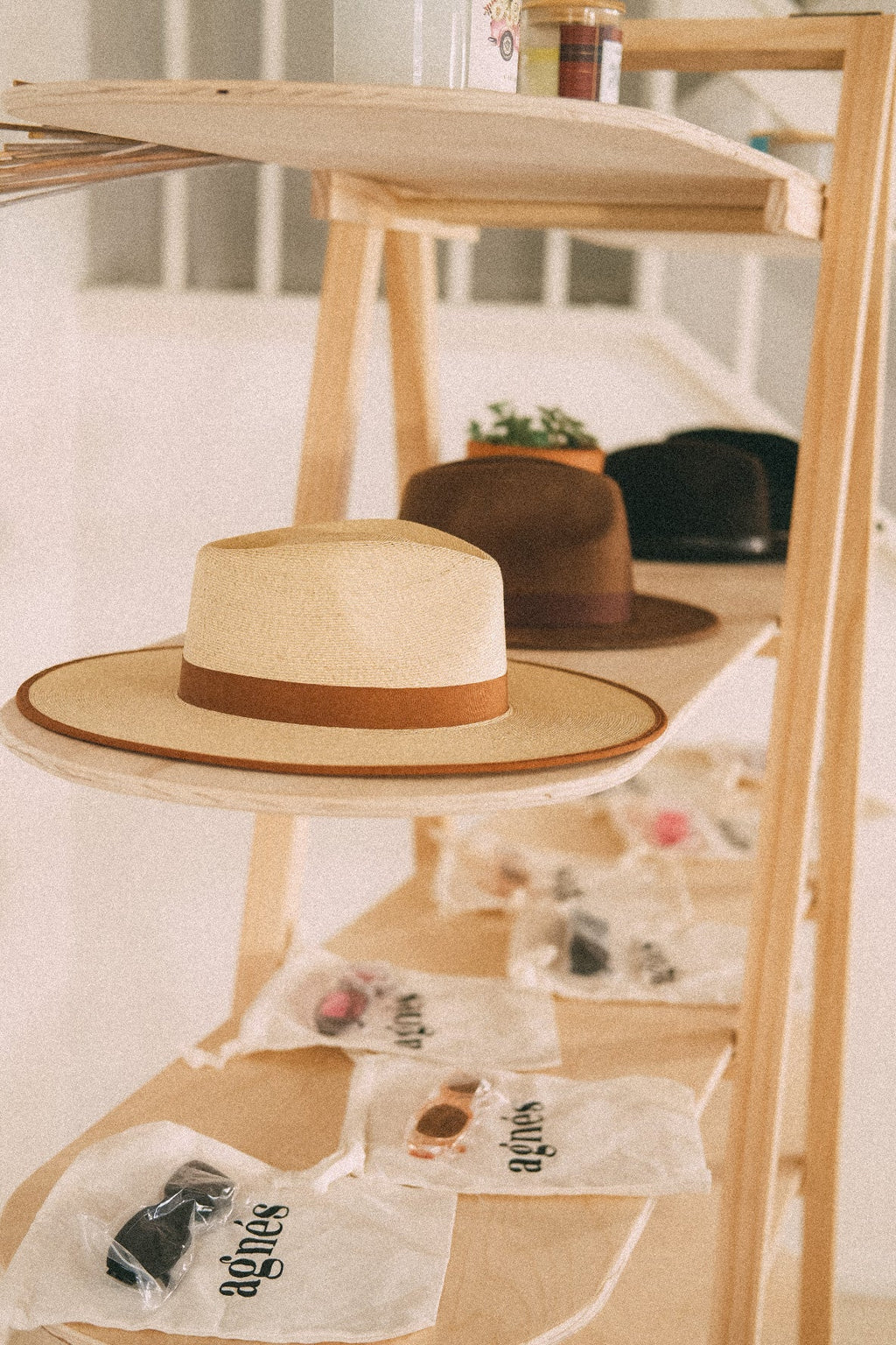 Side view along wooden retail shelves, showing a straw hat at the rounded shelf end and packaged accessories below.