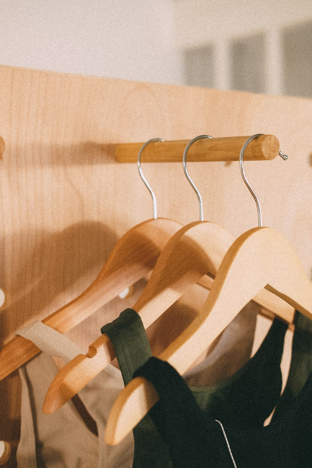 Close-up of wooden hangers holding swimwear on a cylindrical peg fitted into the wooden pegboard.