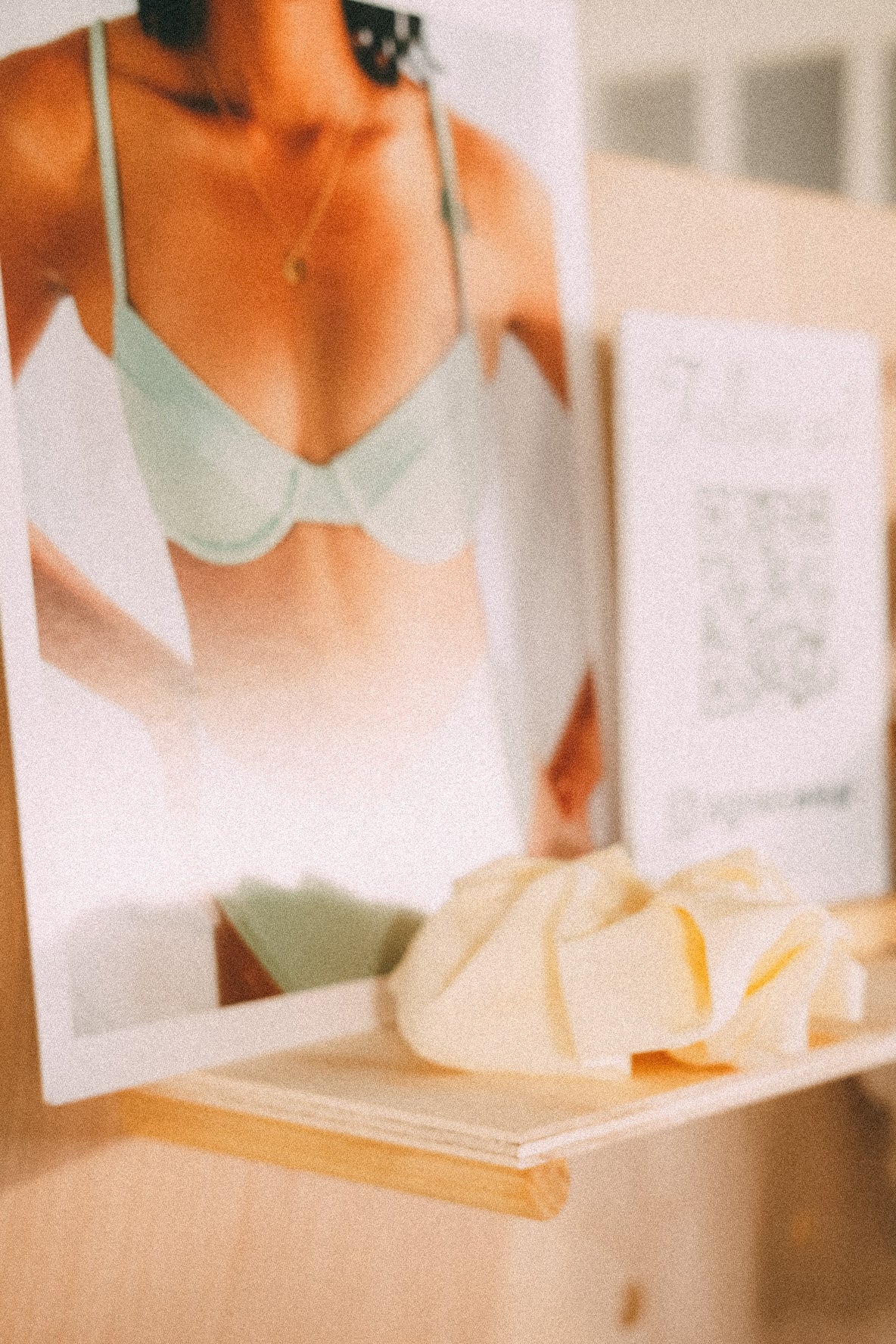 Close-up of a pegboard shelf holding a swimwear promotional print, a QR-code sign and a pale yellow scrunchie.