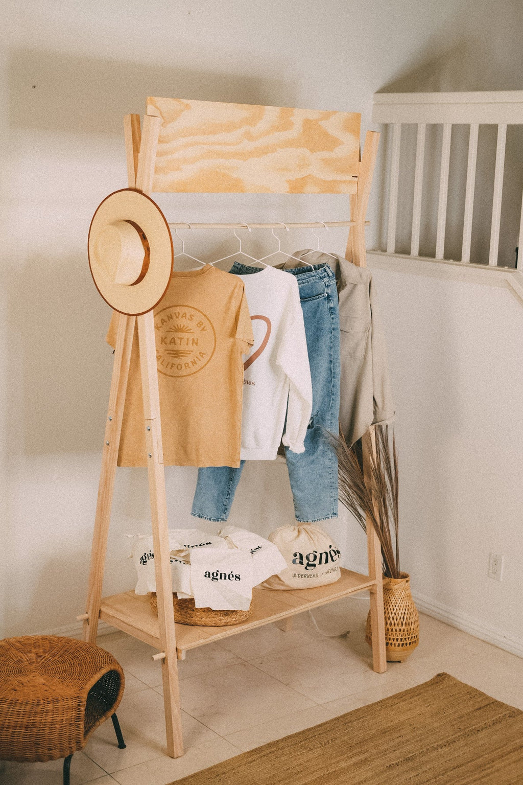STANDRO MCR-4 portable wooden clothing rack with a hanging rail, lower display shelf and blank header board, displaying shirts and jeans.
