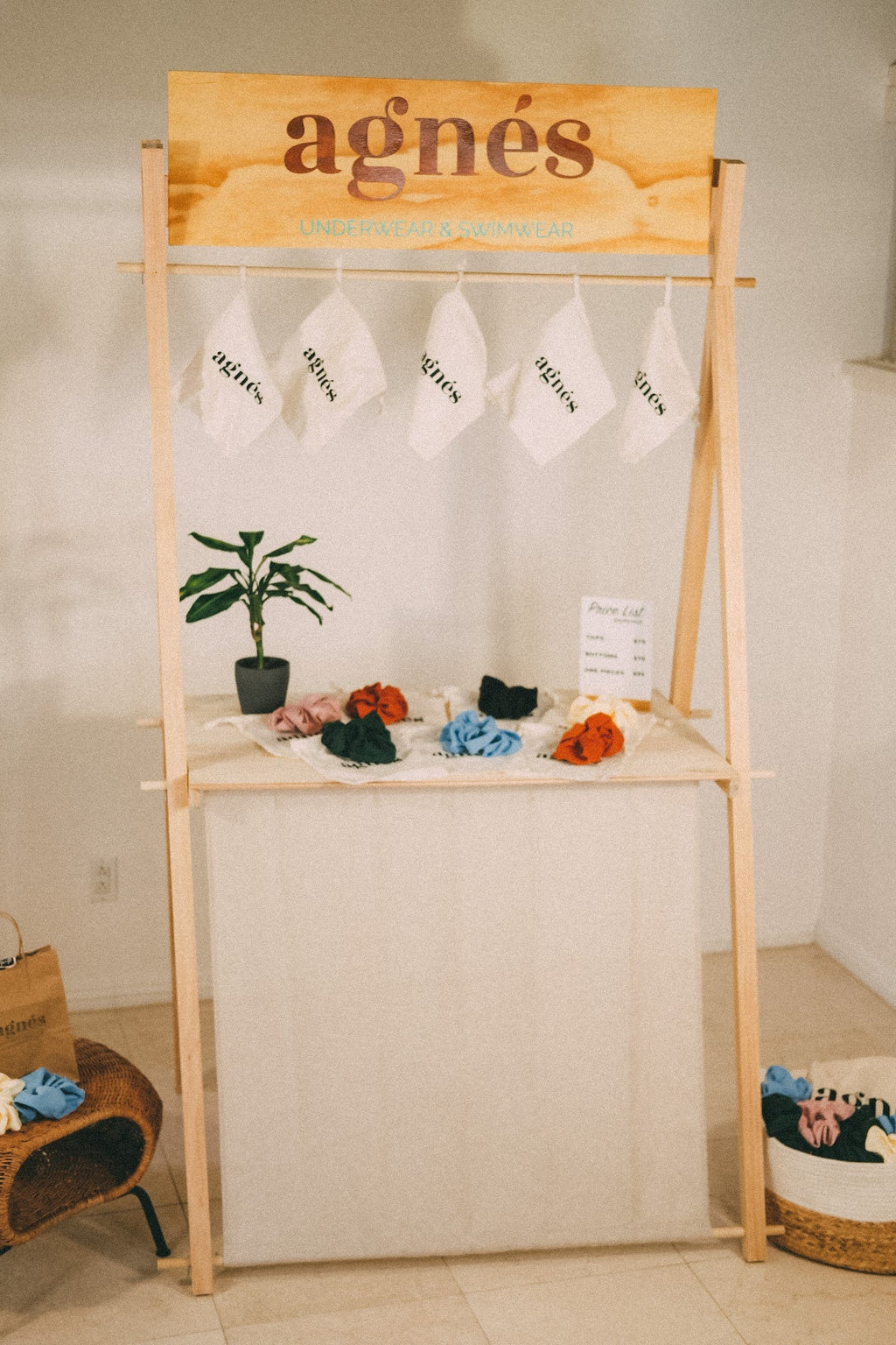 Front view of the EPD-1 market counter with an agnès header, hanging white bags and colorful tabletop accessories.