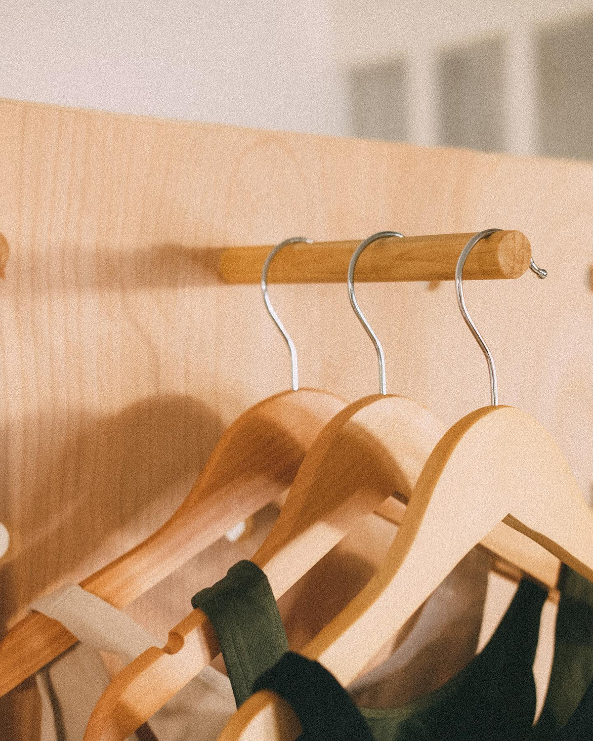 Close-up of wooden hangers holding swimwear on a cylindrical peg fitted into the wooden pegboard.