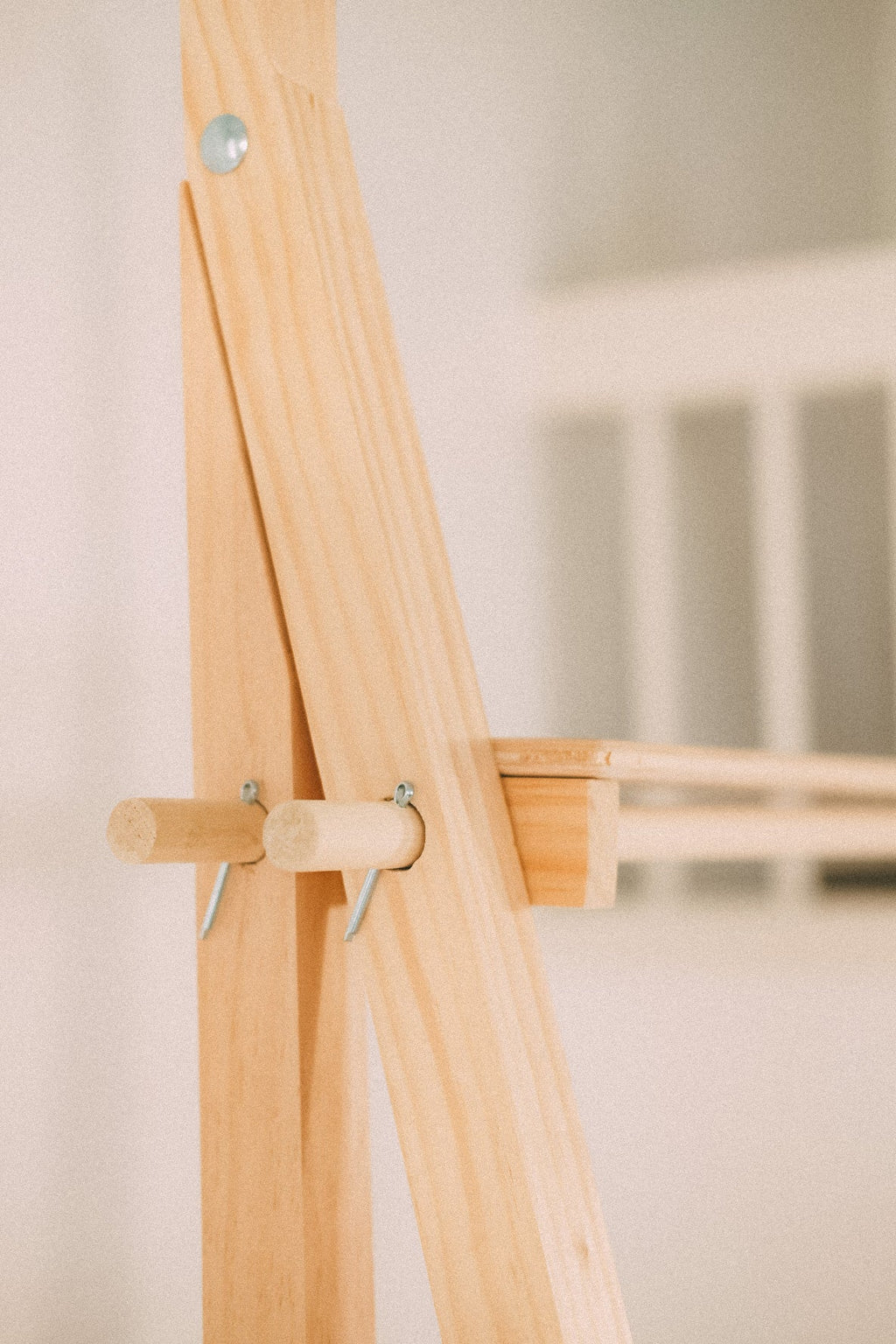 Close-up of a wooden display shelf joint with a projecting wooden pin and metal retaining clip.